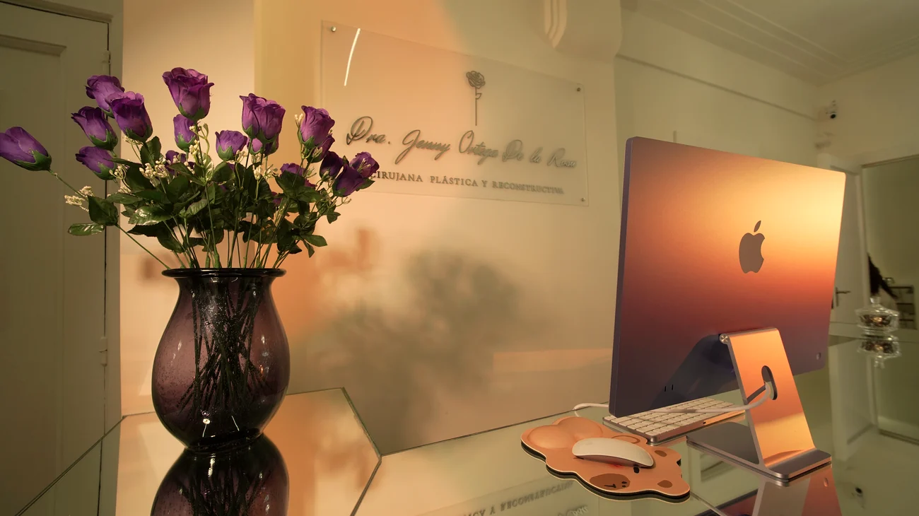 Recepción del consultorio con el cartel de la Dra. Jenny Ortega De La Rosa y rosas lilas